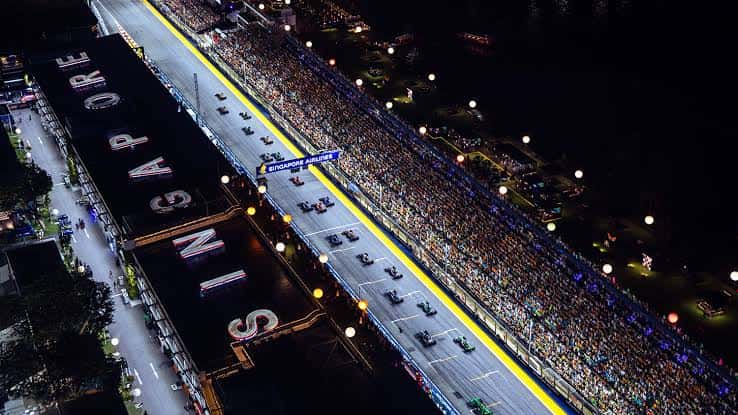 Night-race start on the floodlit Marina Bay Street Circuit, seen from above the Singapore pit building