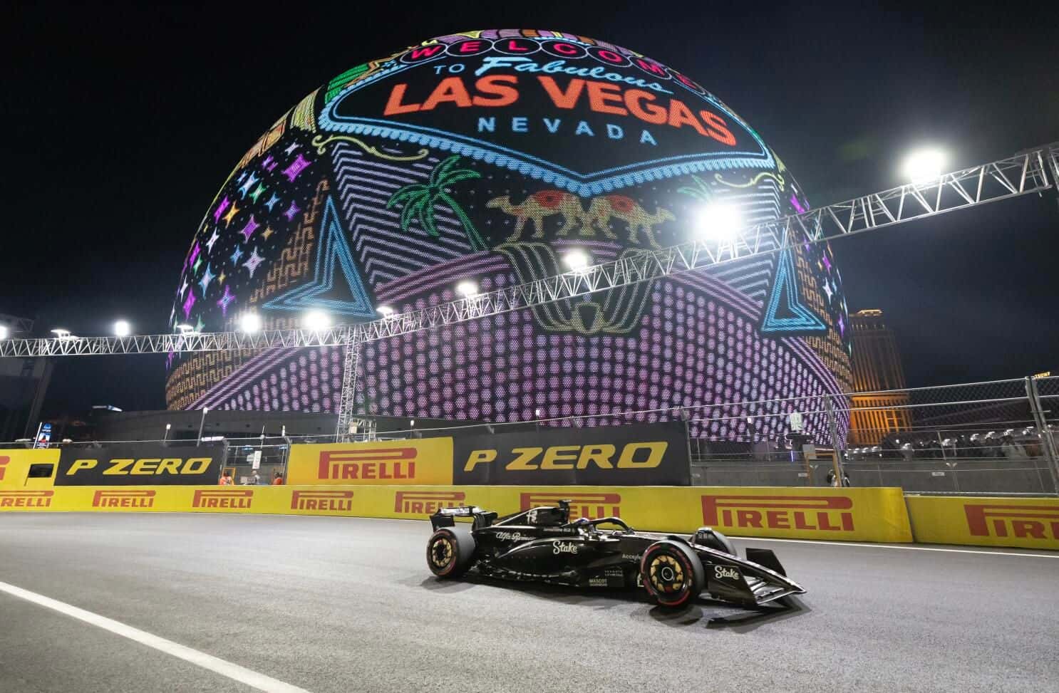 An F1 car races past the glowing Sphere at night on the Las Vegas Street Circuit