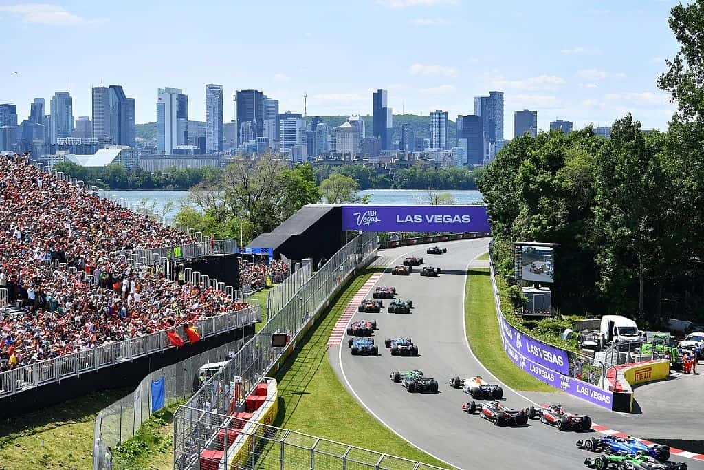 The field streams through the opening corners at Circuit de Gilles Villeneuve, with packed grandstands and the Montreal skyline across the water